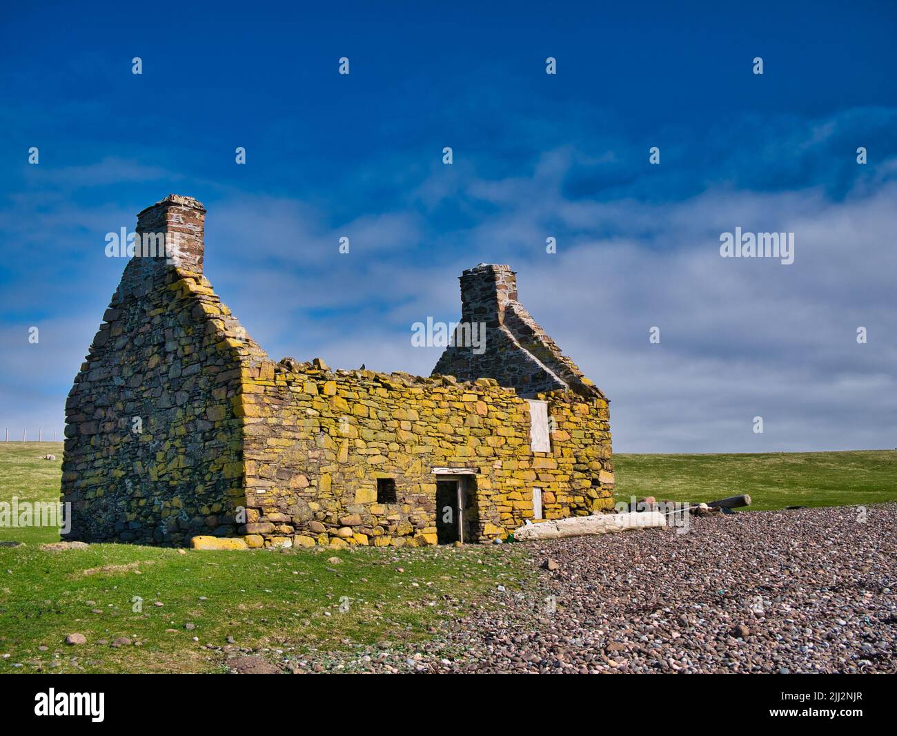 An abandoned, derelict croft or farm house with no roof on a pebble beach at Stenness, Northmavine in  Shetland, Scotland, UK. Stock Photo