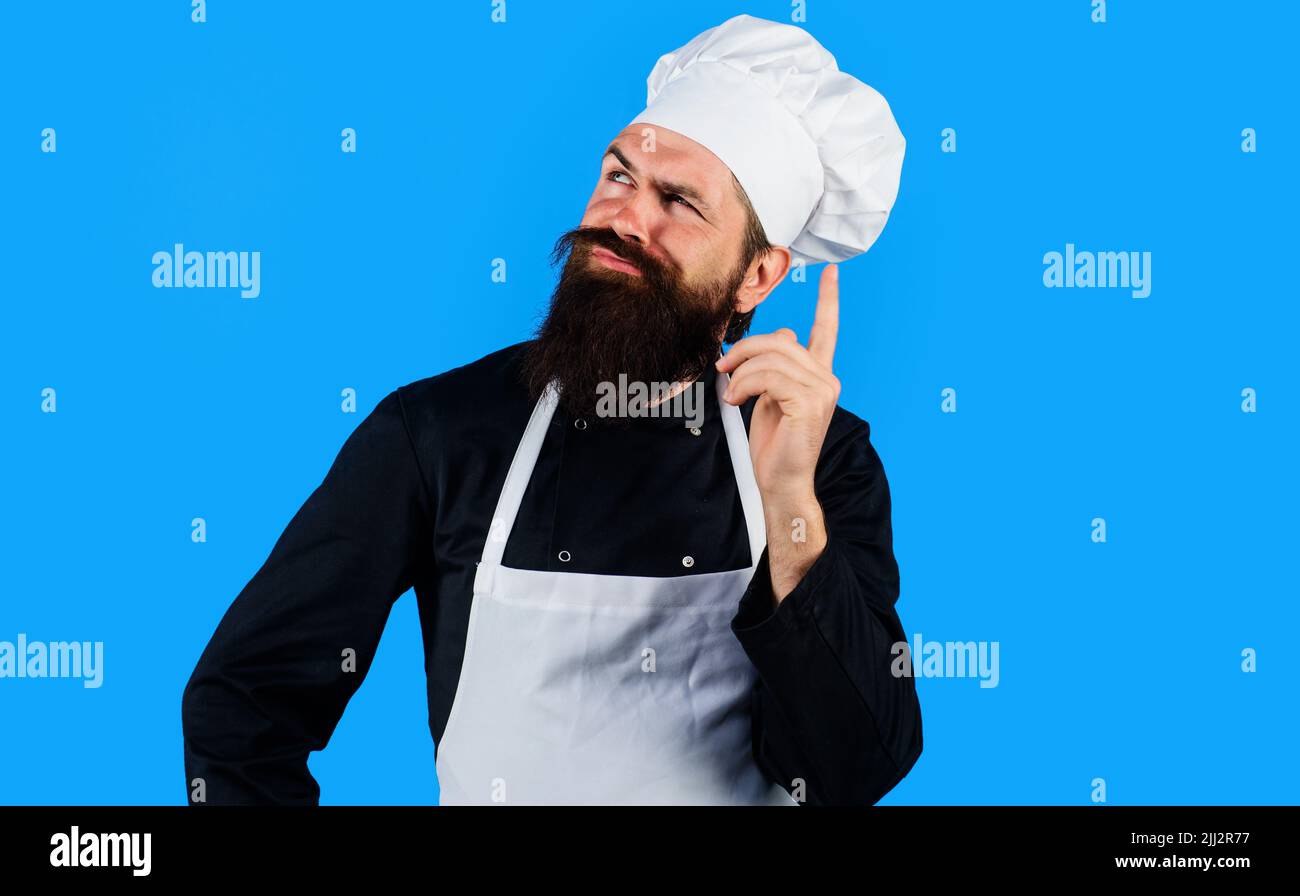 Professional chef in uniform composing new menu. Bearded cook in hat and apron thinks what to cook. Stock Photo