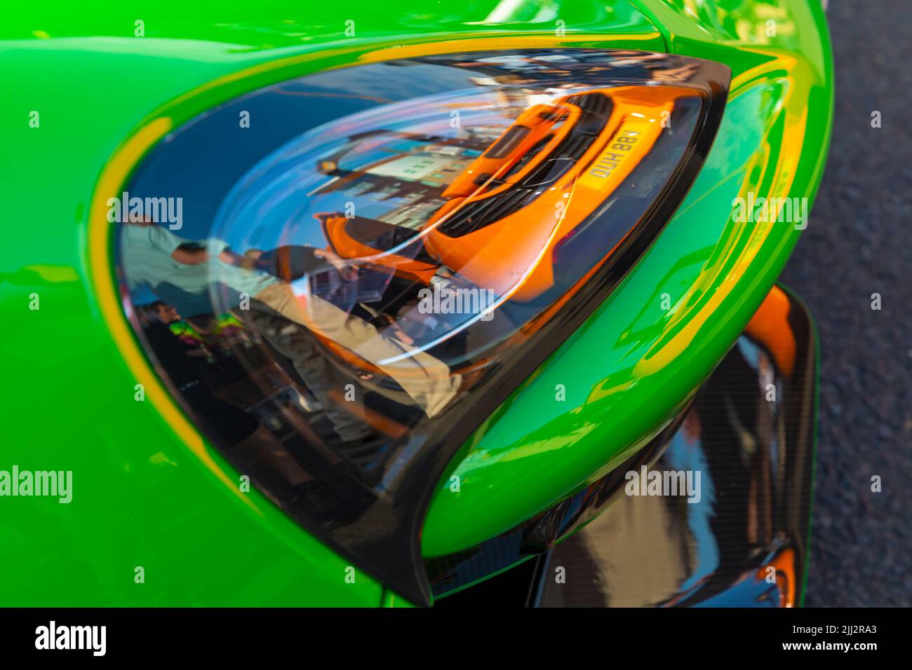 Poole, Dorset UK. 22nd July 2022. Crowds flock to Poole Quay to admire the McLarens supercars for Poole Quay For My Car, a free weekly event during the summer months with a line up of different makes of cars.  Credit: Carolyn Jenkins/Alamy Live News - McLaren car cars Reflection of McLaren supercar reflected in headlight of one parked behind. Stock Photo