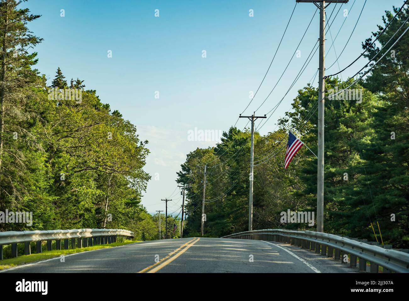 Country main road fading into the horizon distance on a blue sky day, Maine Stock Photo
