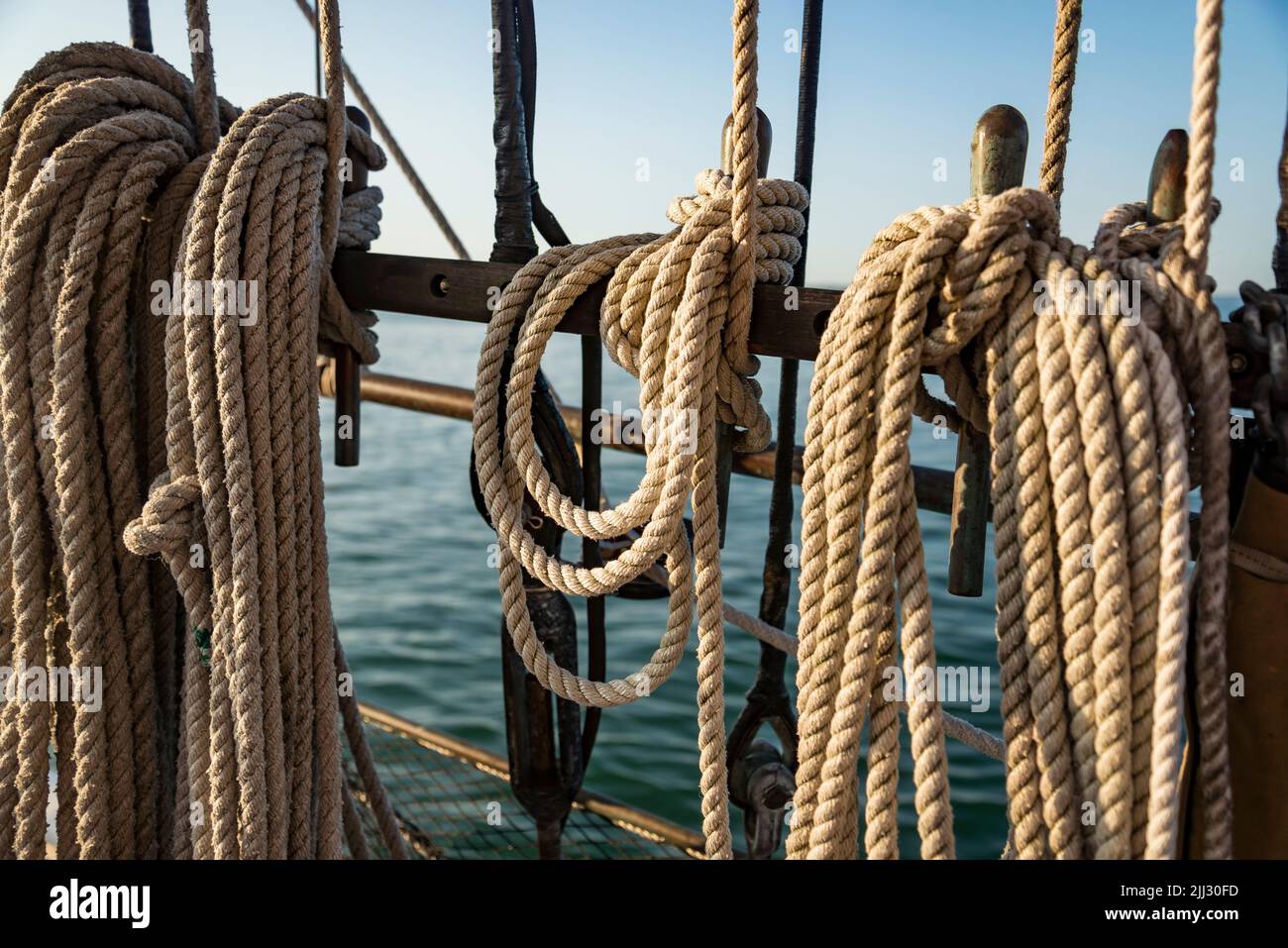 Mooring ropes coiled on a old boat. Strong braided ropes for anchoring the boat in sunset light. Stock Photo