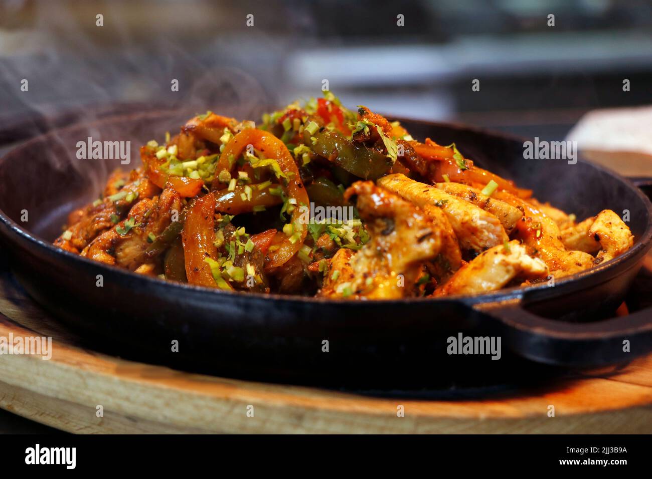 mexican food, chicken fajitas serving on a hot smoking sizzling plate
