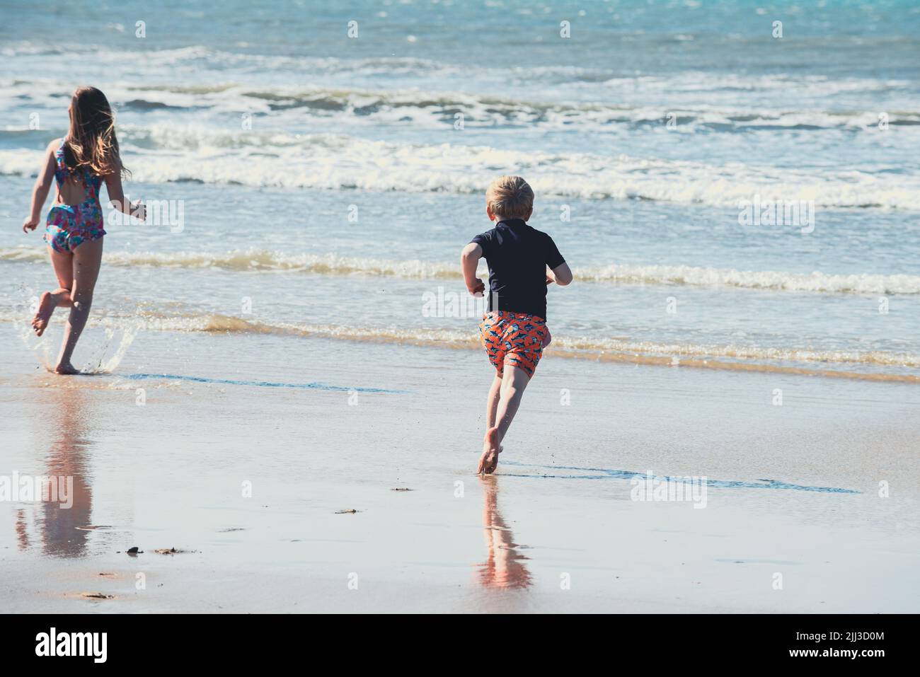Two children run to the sea to swim while on summer vacation Stock Photo
