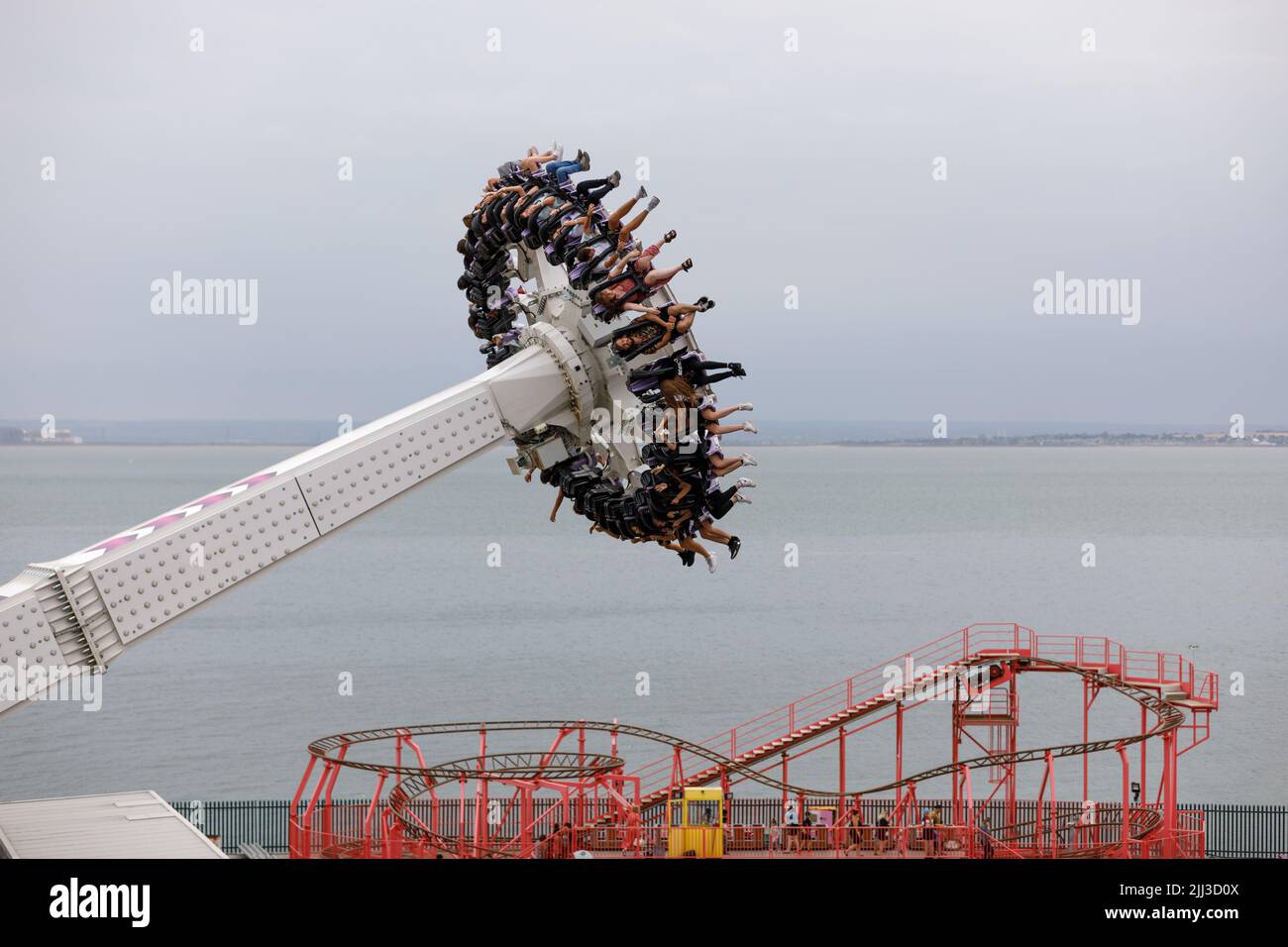 A pendulum ride gondola mid air with people hanging upside down with legs in the air. Stock Photo