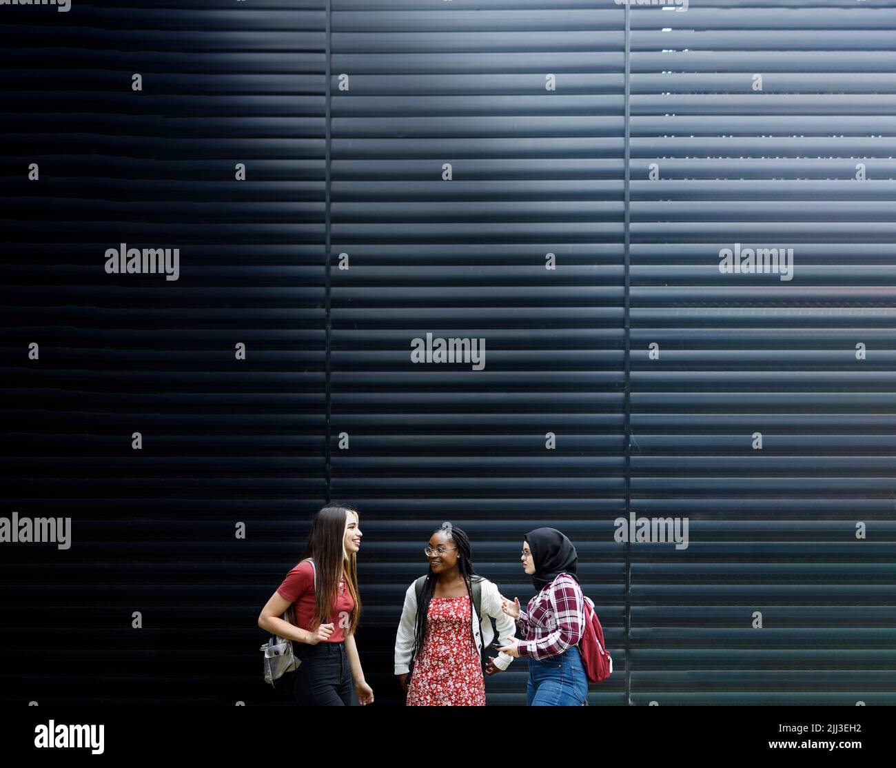 Three students of various ethnic groups talking together Stock Photo