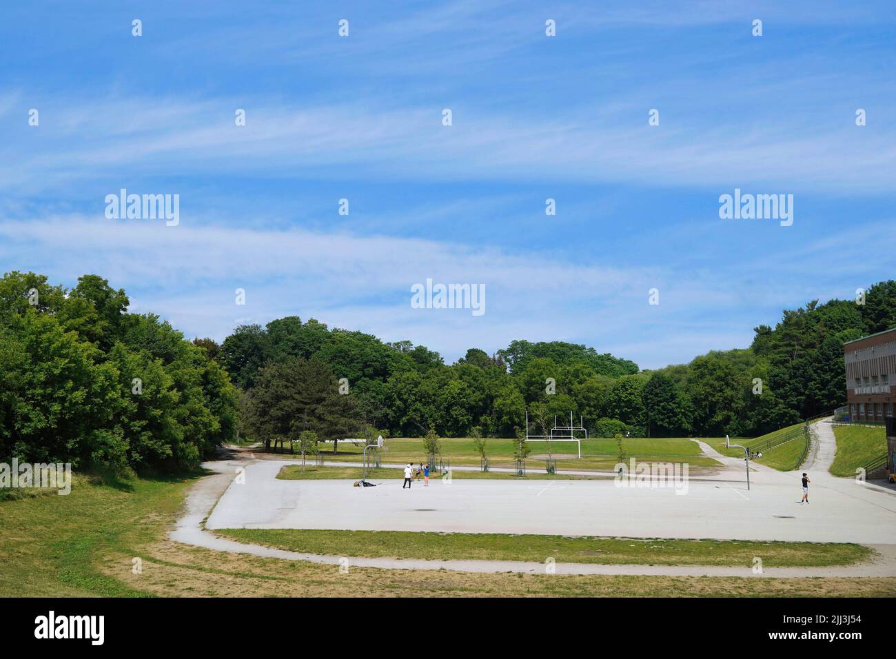 Sports field beside a school, surrounded by trees Stock Photo