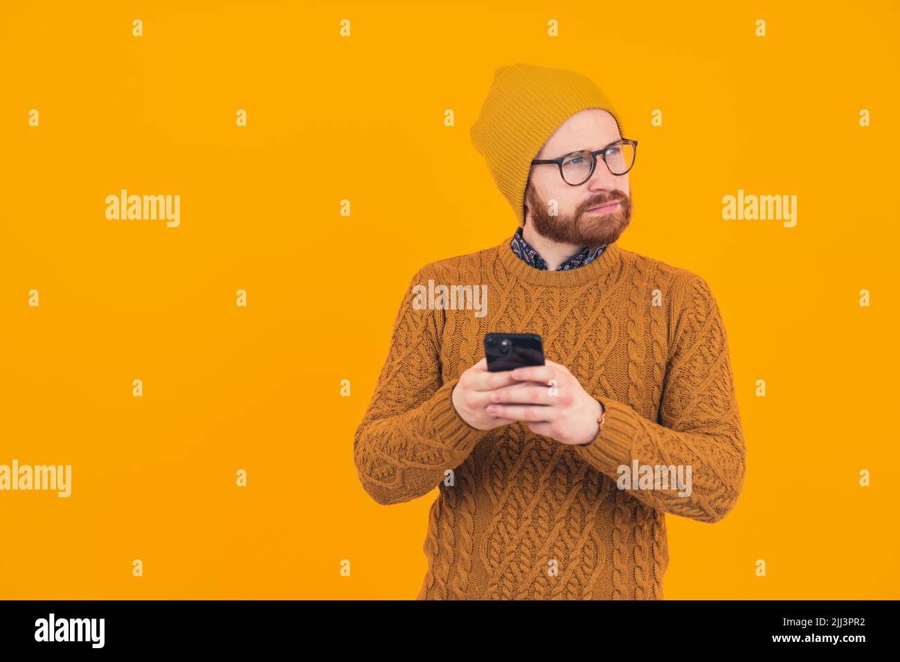 Young stylish online trader investor thinking about new investments and trades - passive income concept - orange background. High quality photo Stock Photo