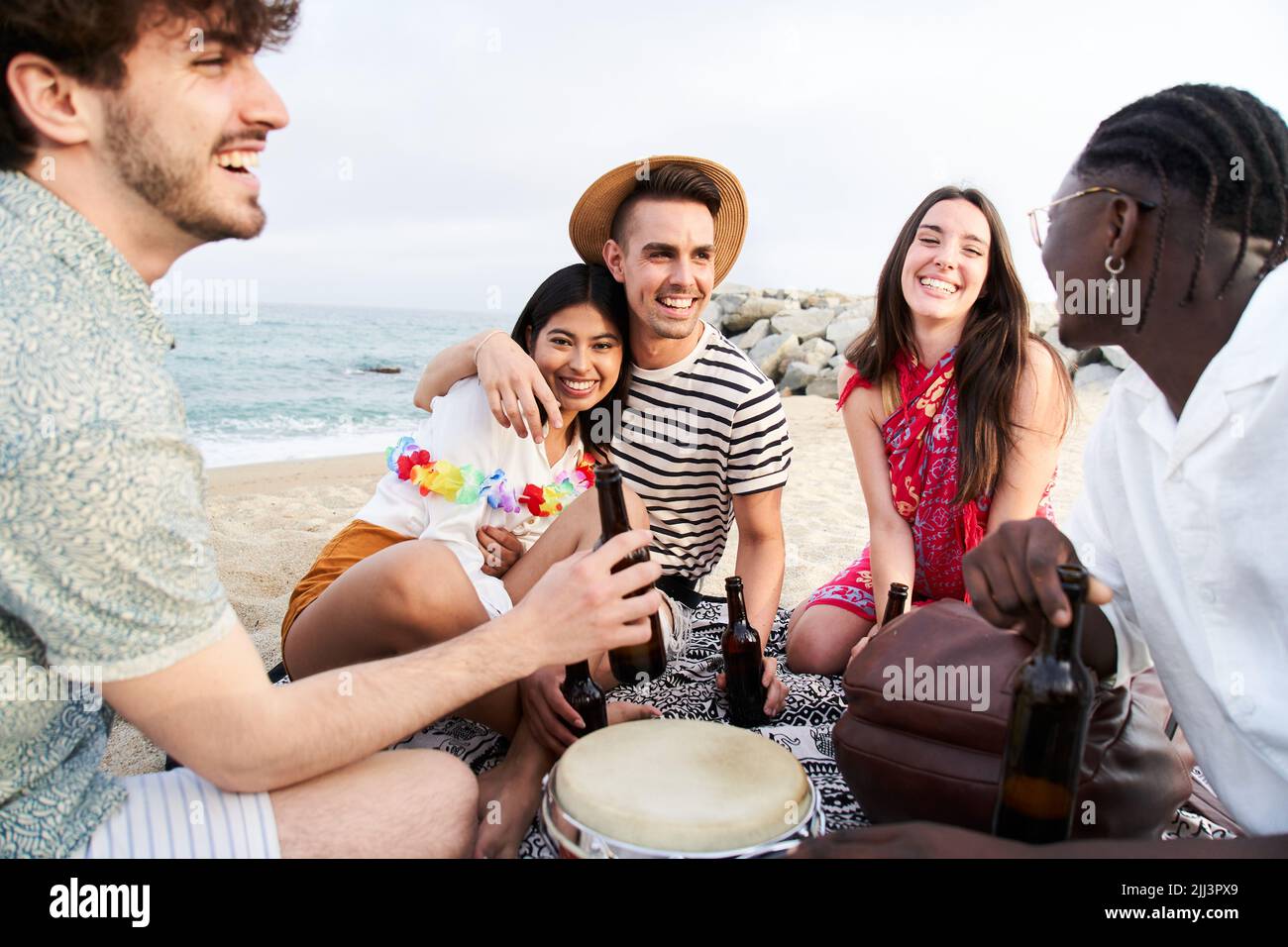 People Celebration Beach Party Summer Holiday Concept. Five beautiful friends cheers and drink beers near the sea, enjoying vacation time laughing and Stock Photo