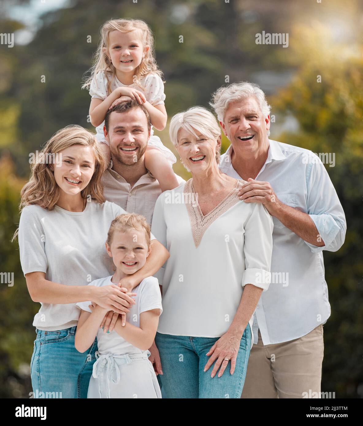 Mature and young family members outside in the garden. Happy smiling parents relaxing outside with their children. Portrait of content grandparents Stock Photo
