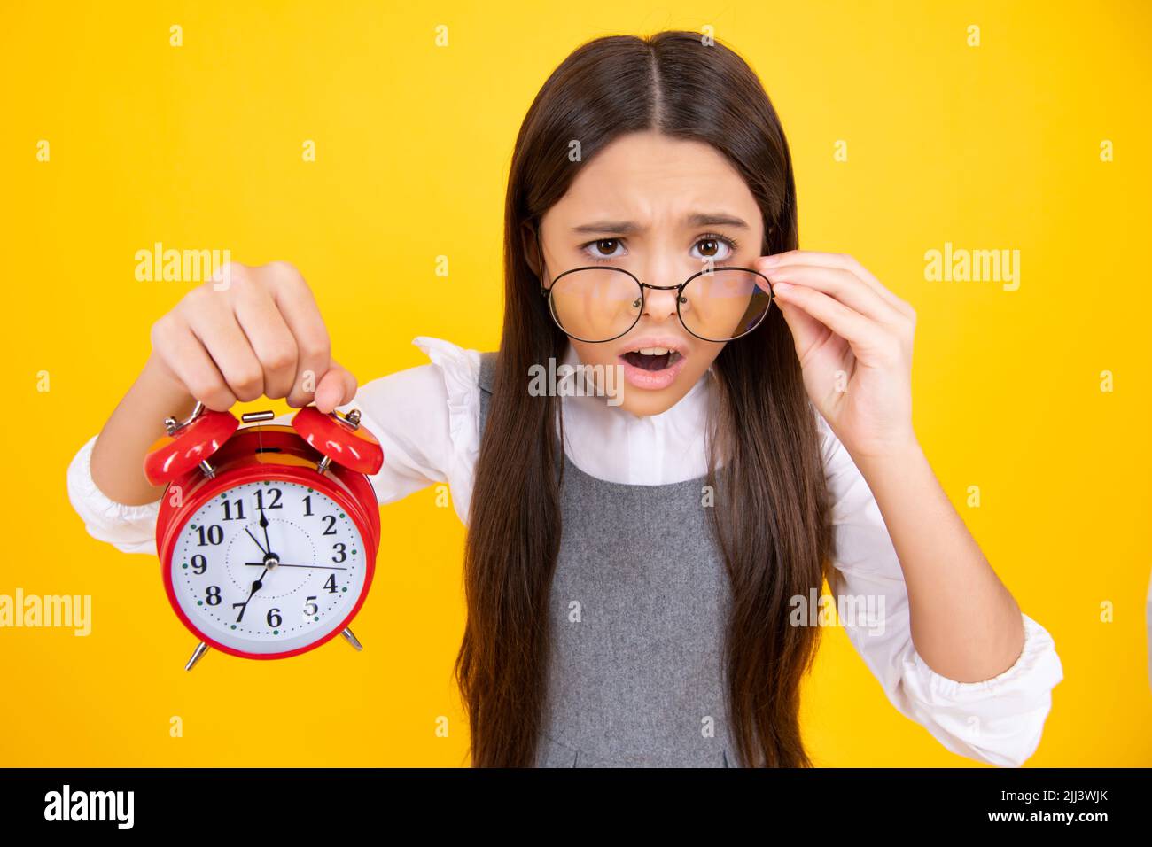Teen student girl hold clock isolated on yellow background. Time to