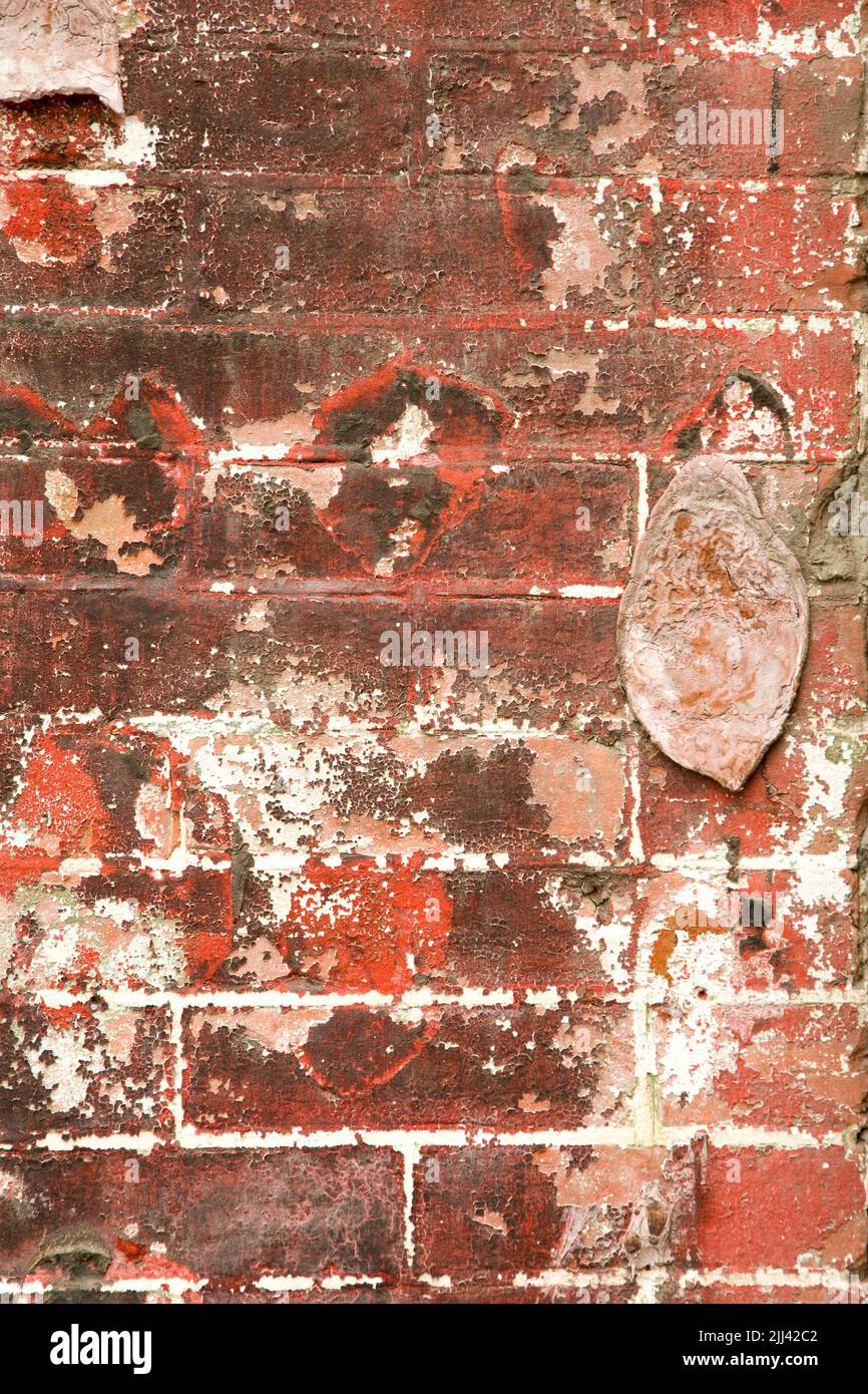 Dirty old brick wall with chipped brick, stains, and paint Stock Photo