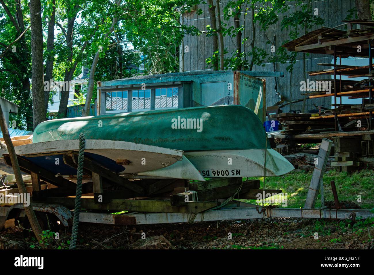 Small boats stacked on a trailer in the woods at the Essex Shipbuilding