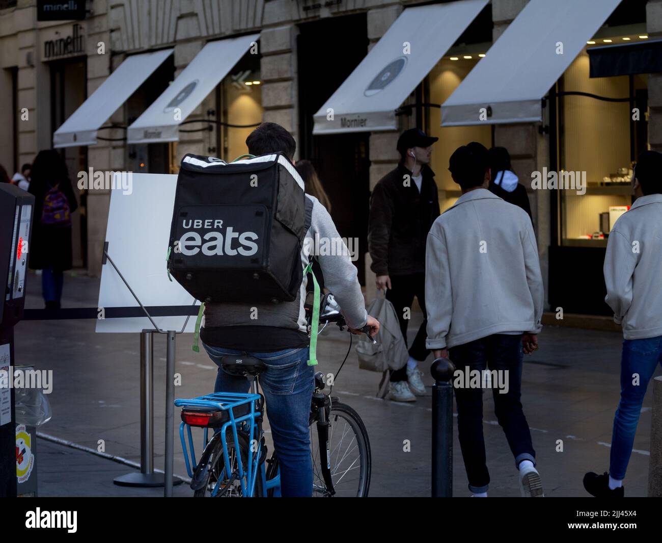 Picture of a man on a bicycle wearing a bag with the logo of Uber Eats for a deliveryin Bordeaux, France. Uber Eats is an American online food orderin Stock Photo