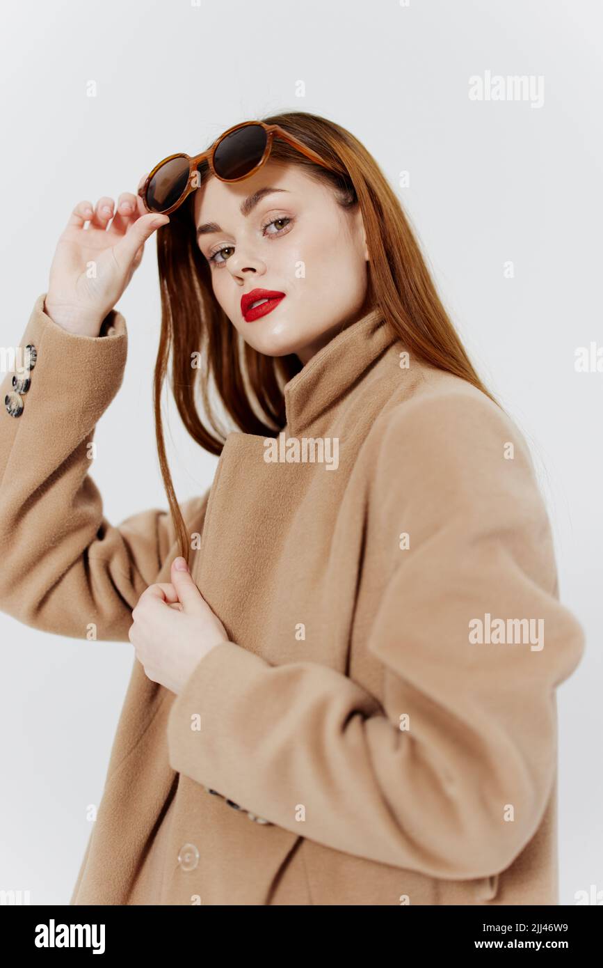 A femme fatale in a coat poses on a white background in the studio  advertising a clothing brand Stock Photo - Alamy