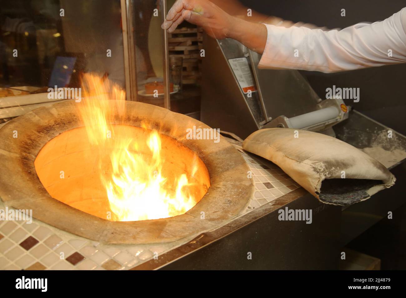 Baker making Turkish pita bread in tandoor (clay oven) at Istanbul Turkey. Stock Photo