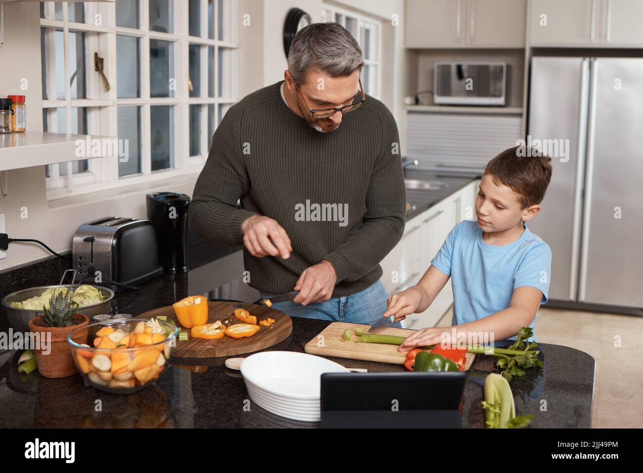 Its mothers day and were cooking dinner. a little boy cooking with his father at home. Stock Photo