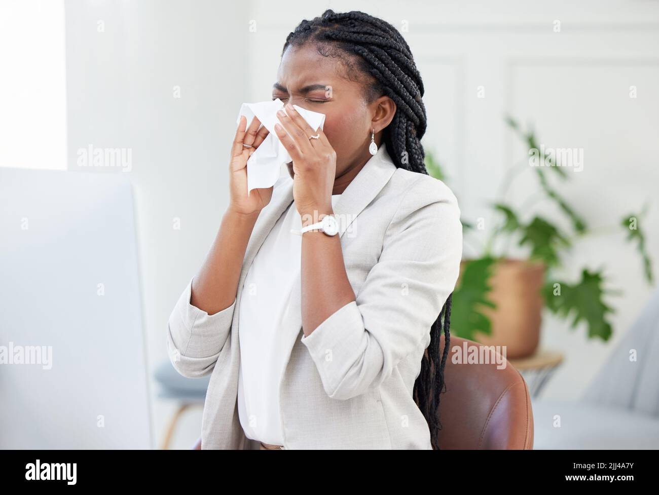Allergy season is upon us. a businesswoman blowing her nose due to a