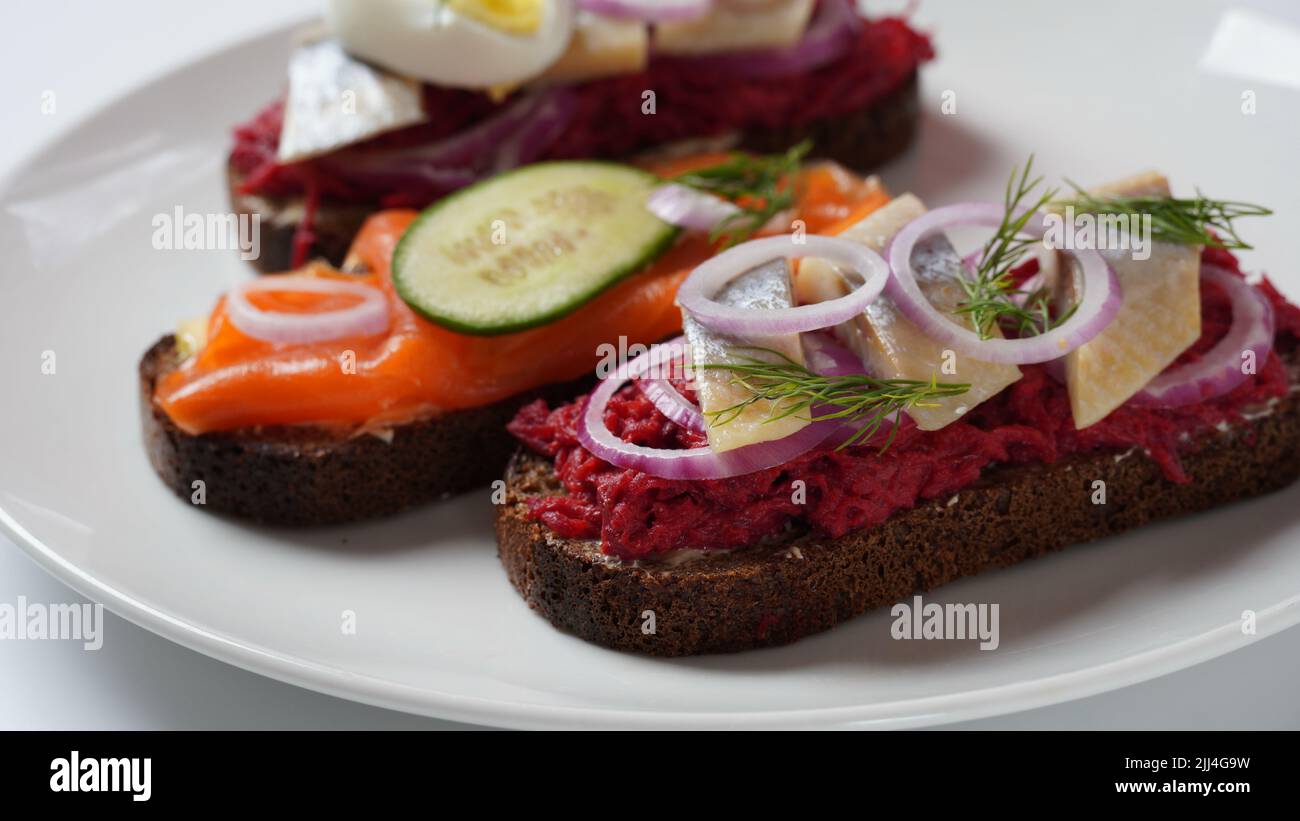Danish open sandwich Smorrebrod on dark rye bread with herring, salmon