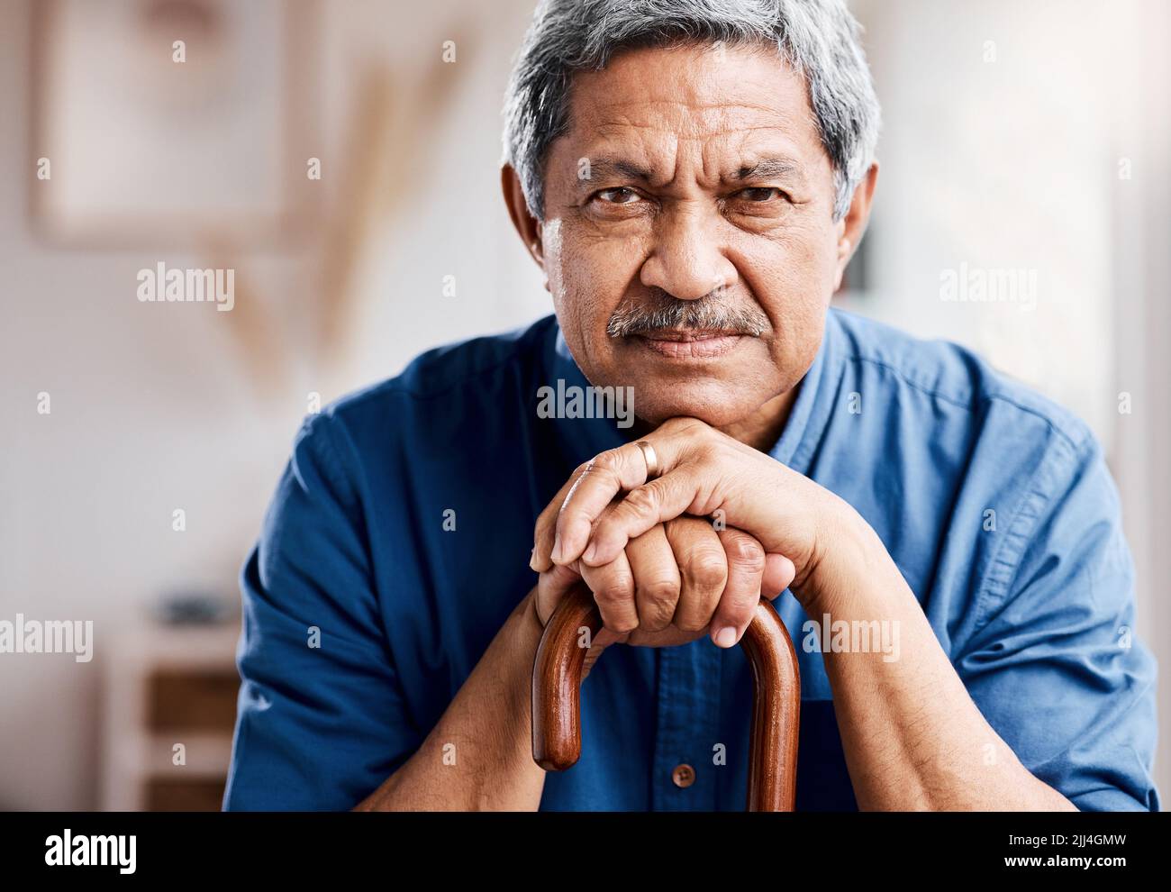 I dont have time for your questions. a senior man leaning in his walking stick at home. Stock Photo
