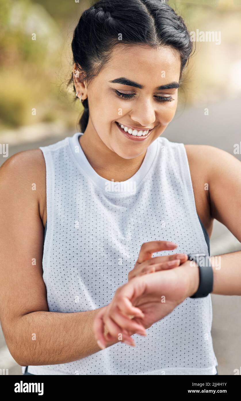 Im happy with that. a young woman checking her watch while out for a run. Stock Photo