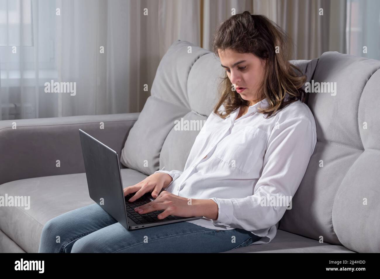 Disabled woman works on computer sitting on sofa at home Stock Photo ...