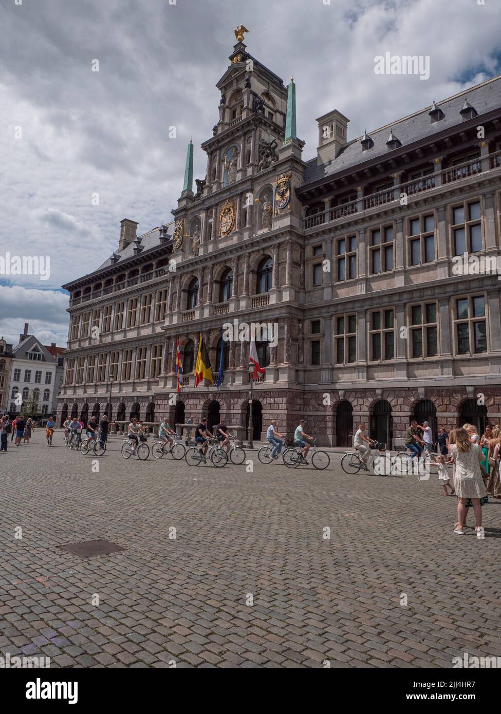 Antwerp, Belgium, 02 July 2022, Cyclists pass the town hall on the big market square of Antwerp Stock Photo