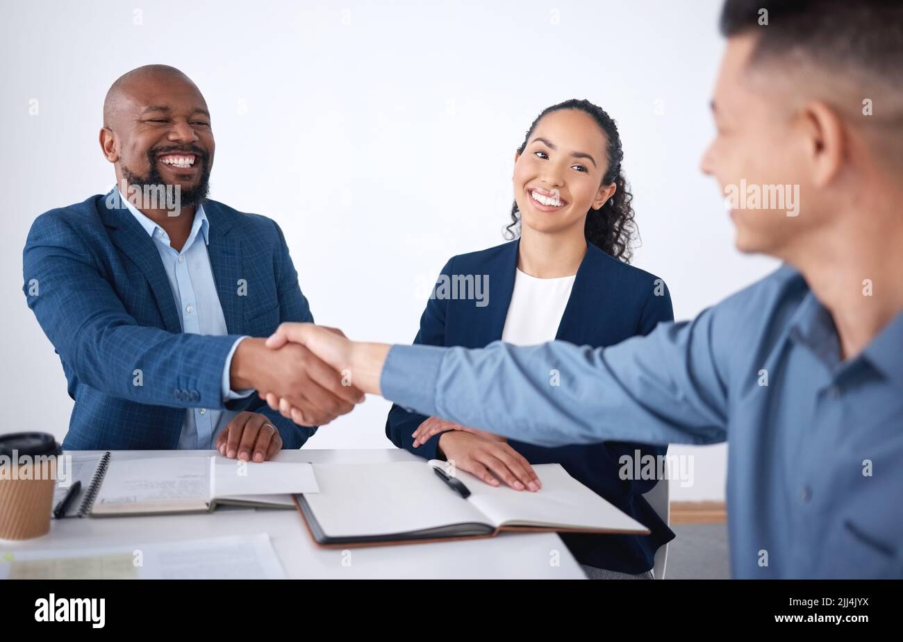 Team of smiling diverse business people shaking hands in office after meeting in boardroom. Group of happy professionals and colleagues using Stock Photo