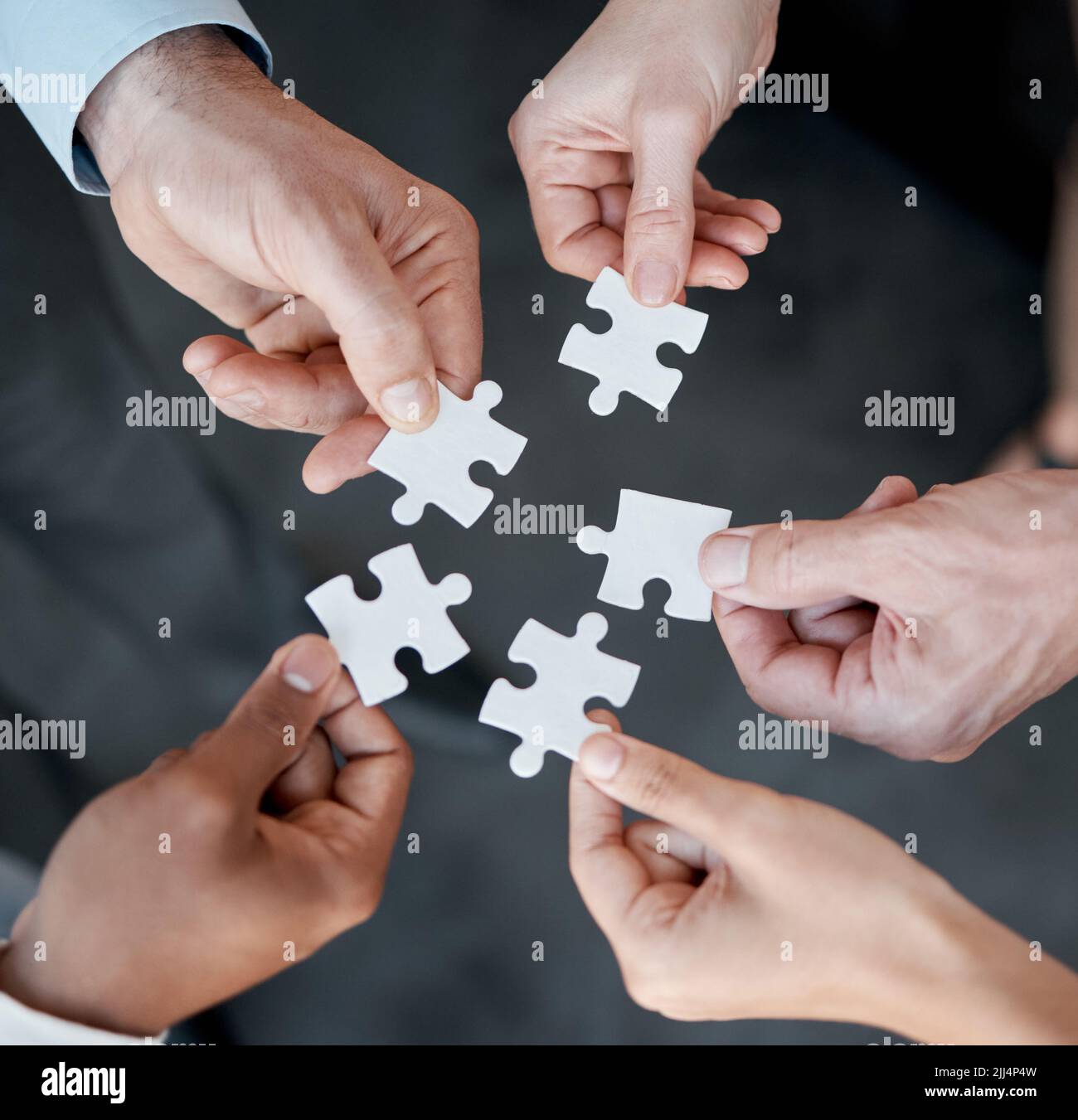 Building a legacy piece by piece. five unrecognizable businesspeople building a puzzle in the office. Stock Photo