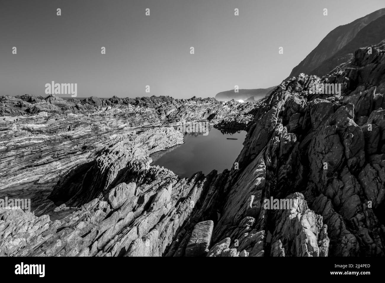 Black and white view of the Looking Jagged Rocky Coastline of the Tsitsikamma section of the Garden Route National Park, South Africa Stock Photo