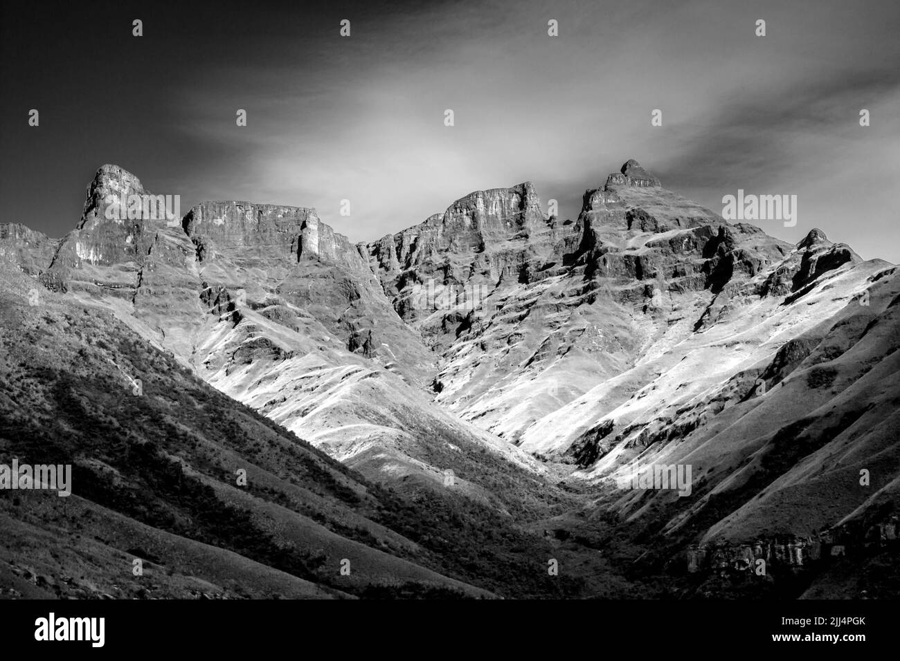 Black and White view of the tall craggy cliffs in the Injisuti region of the Drakensberg Mountains on a clear sunny day Stock Photo