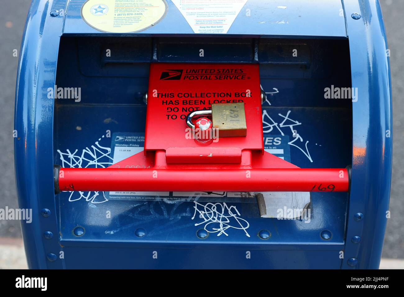 A USPS mailbox with a red security locking device. A locked collection mailbox in New York with mail not being collected at this location. Stock Photo