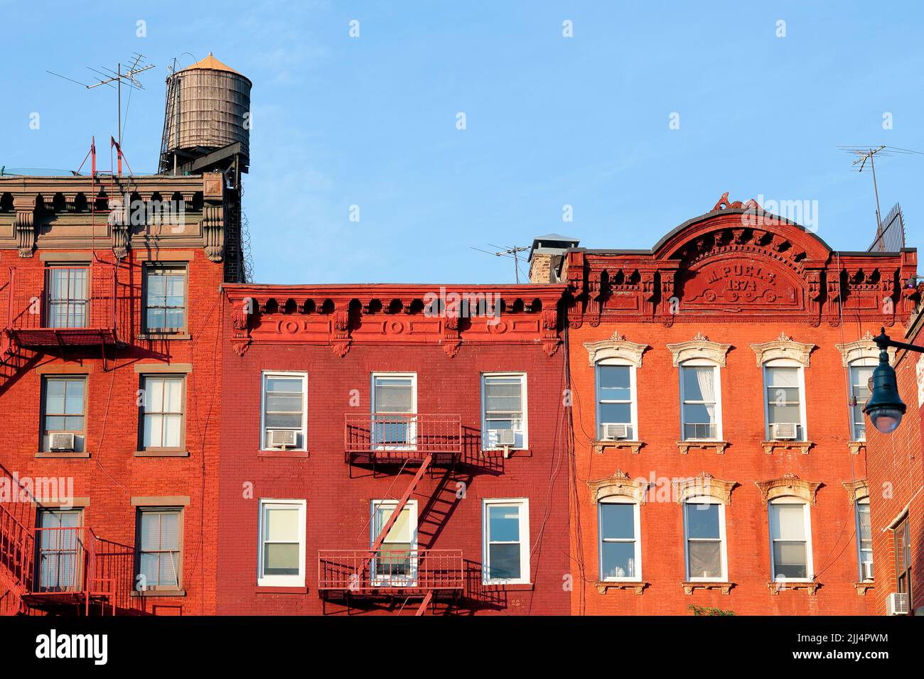 New York City tenement buildings in Manhattan's Greenwich Village neighborhood near sunset with wooden water tank and rooftop tv attennas. Stock Photo