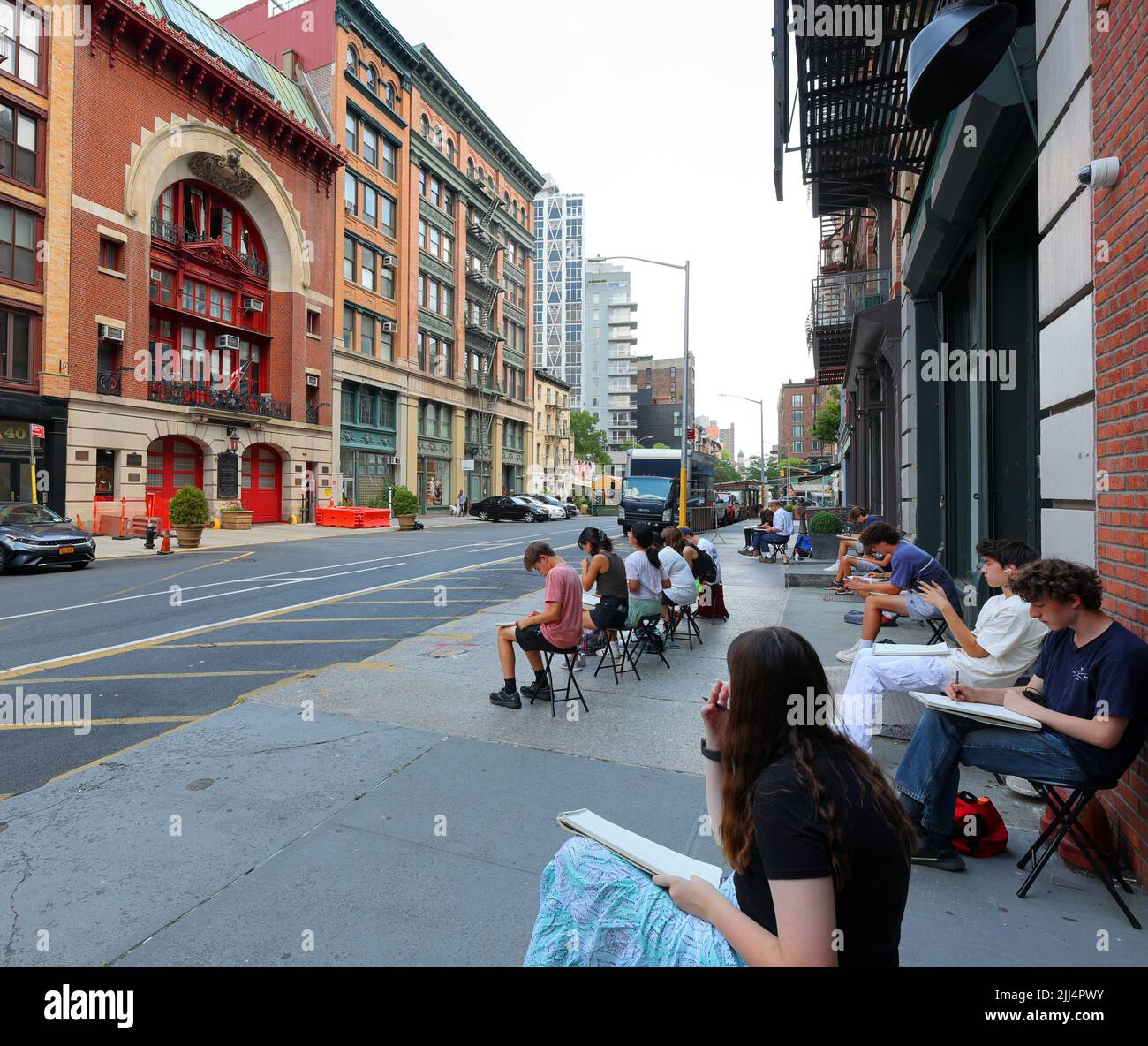 Art students with sketchpads drawing the firehouse on Great Jones St in Manhattan, New York, July 20, 2022. Stock Photo