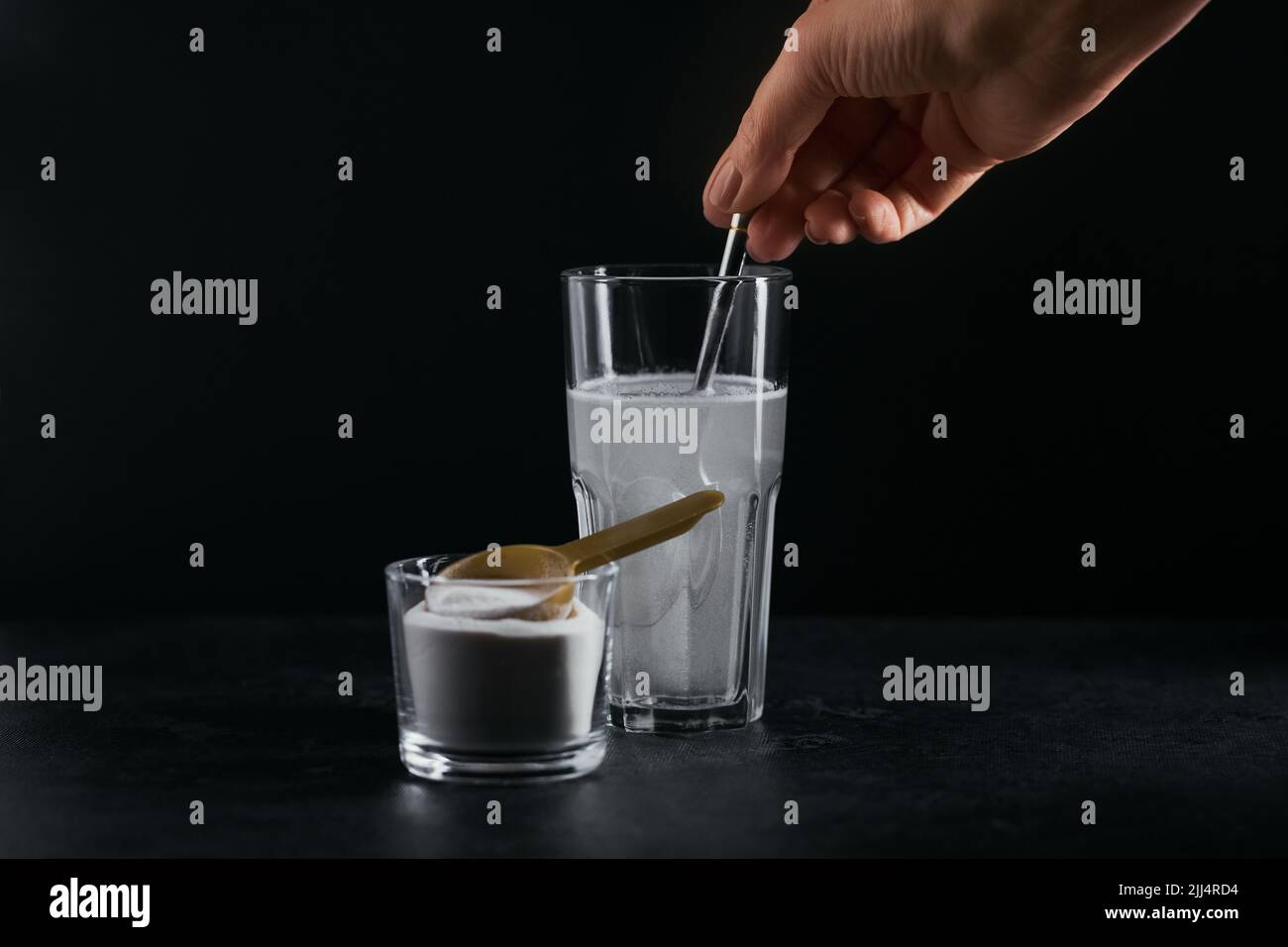 Glass with collagen dissolved in water and collagen protein powder on black background Stock Photo