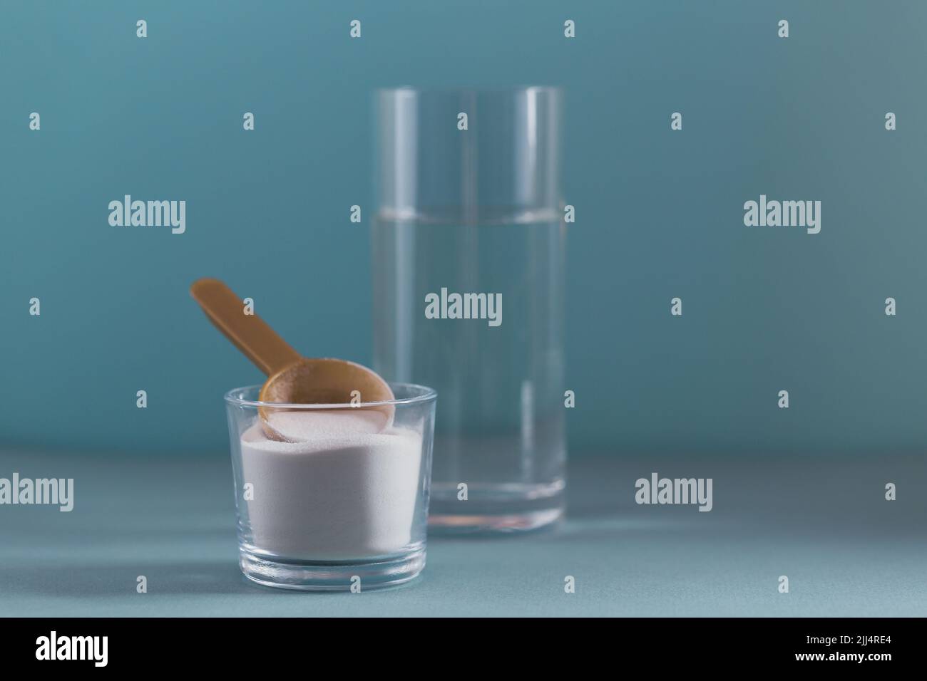 Collagen powder in bowl, glass of water and measure spoon on light blue background Stock Photo