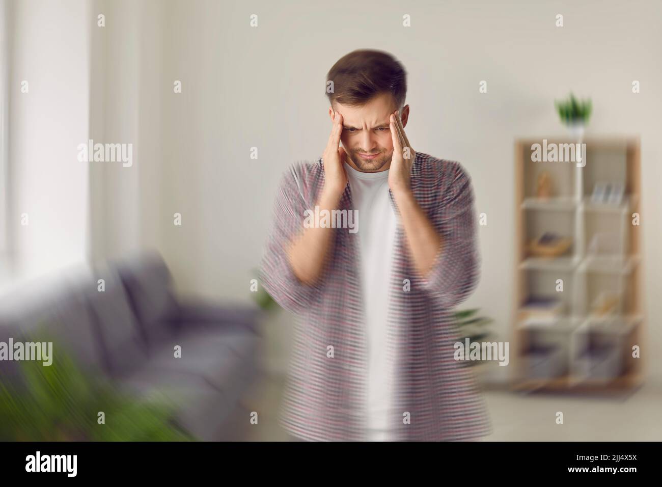 Young man feels sudden pain, dizziness and spinning vertigo sensation in his head Stock Photo