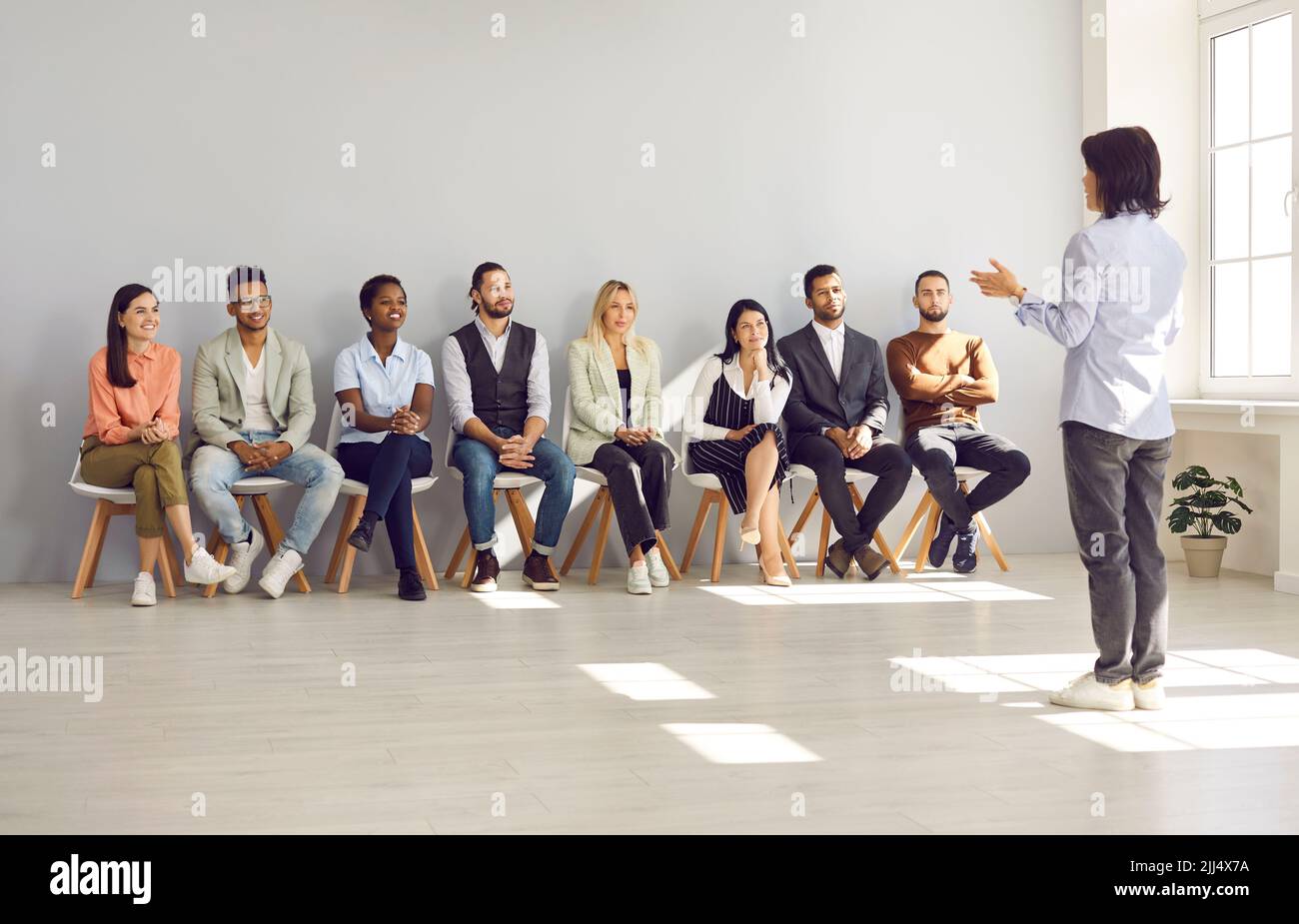 Business speaker or psychologist giving a speech for young diverse men and women Stock Photo