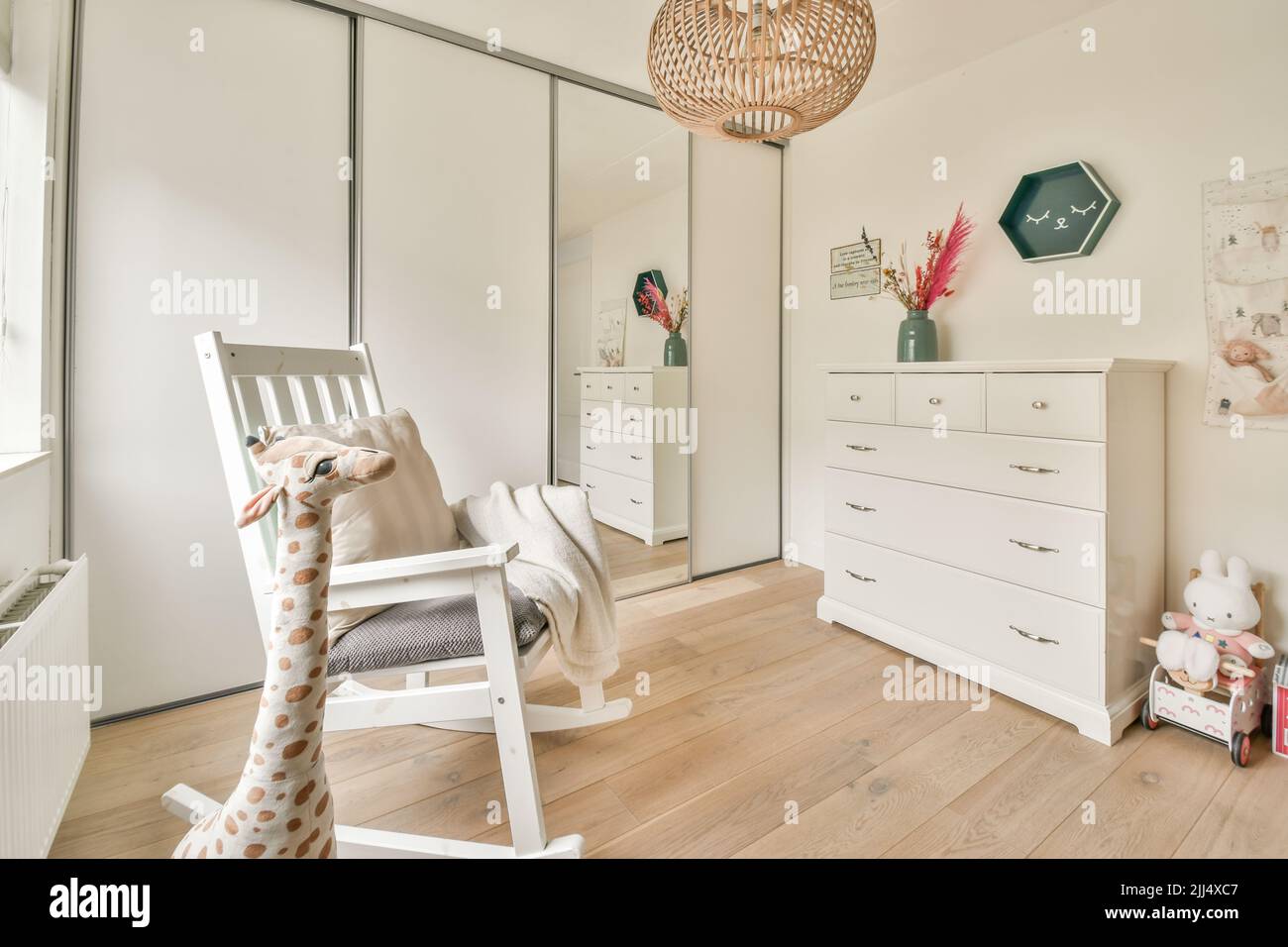 Interior of white room with baby crib and armchair near window in