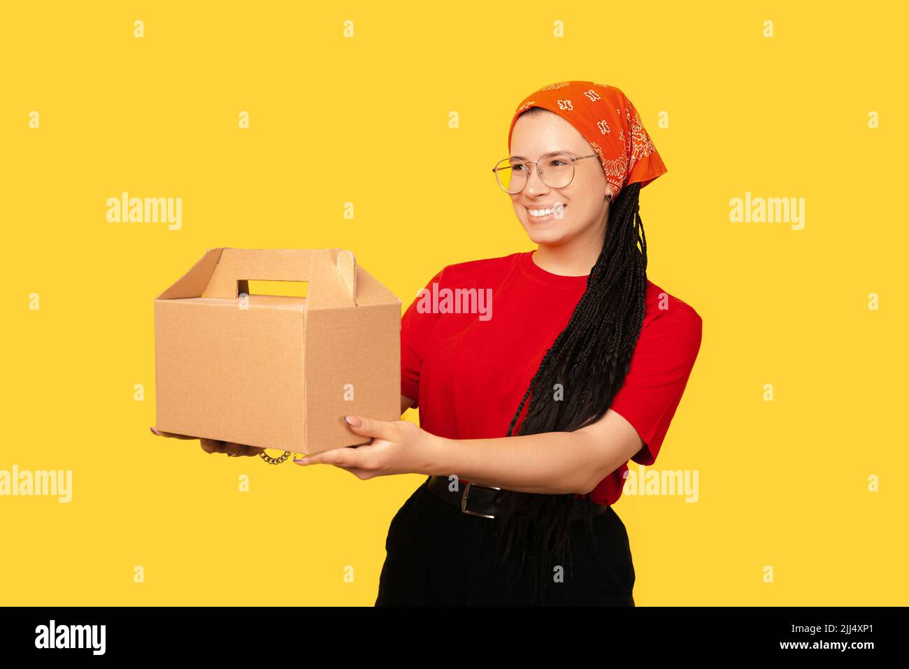 A photo of a girl with box braids giving happily someone their delivery Stock Photo