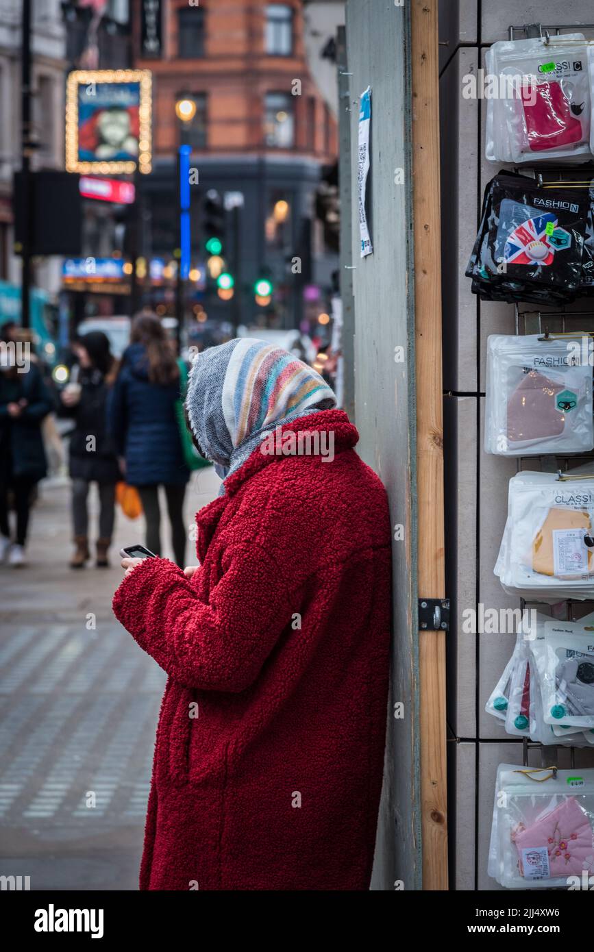 lady texting whilst wrapped up in the cold Stock Photo