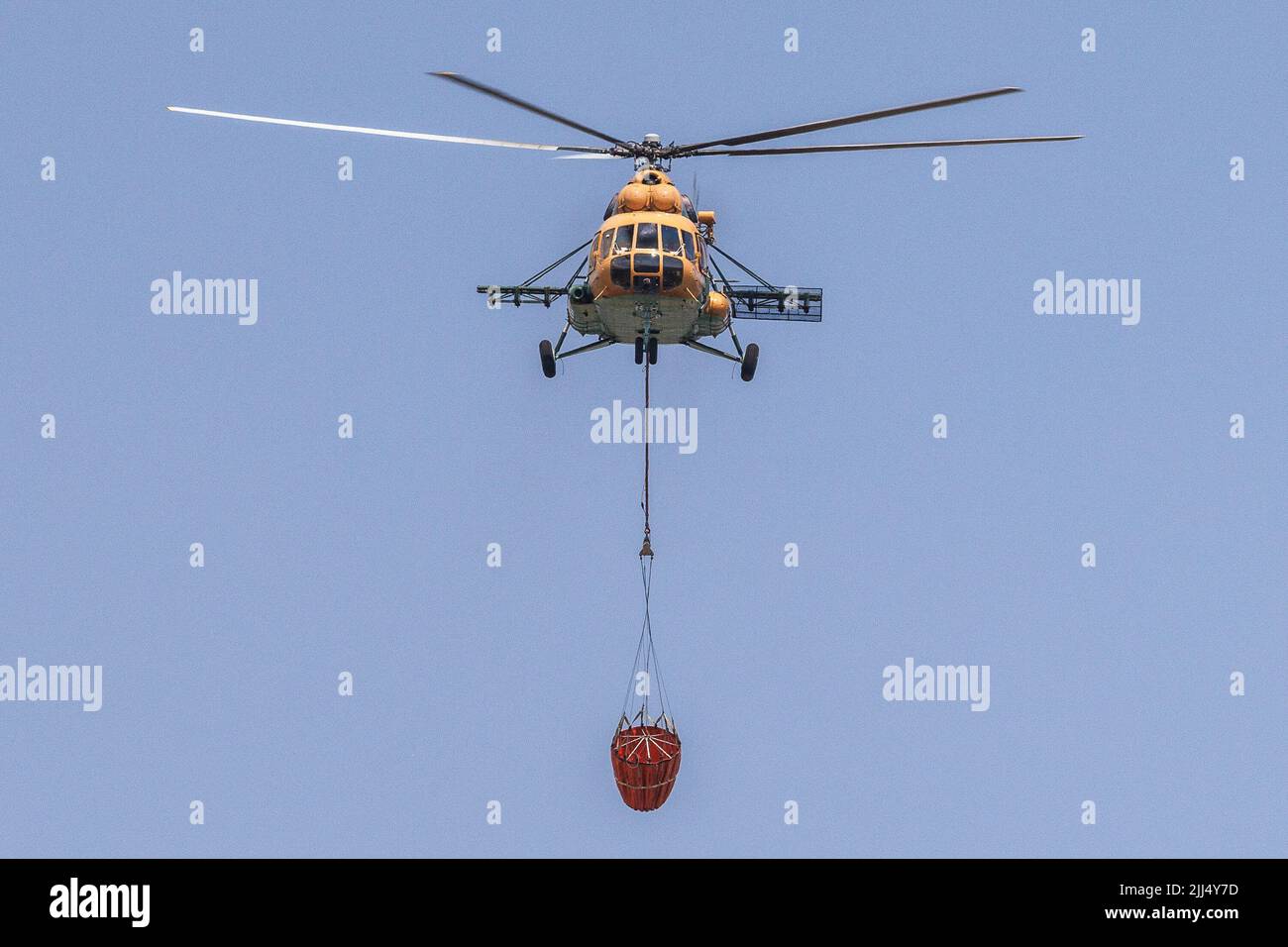 Karst, Slovenia. 22nd July, 2022. A Hungarian Mil Mi-17 helicopter carries a Bambi bucket for extinguishing fires as it flies over a large wildfire that burns near the village of Temnica in the Karst region of Slovenia. About a thousand firemen with air support from three Slovenian helicopters, two Serbian helicopters, an Austrian helicopter, a Slovakian Black Hawk helicopter and two Hungarian helicopters, a Croatian Canadair firefighting airplane and a Slovenian army Pilatus airplane continued battling a large wildfire that broke out five days ago and has intensified in the Karst region of Sl Stock Photo