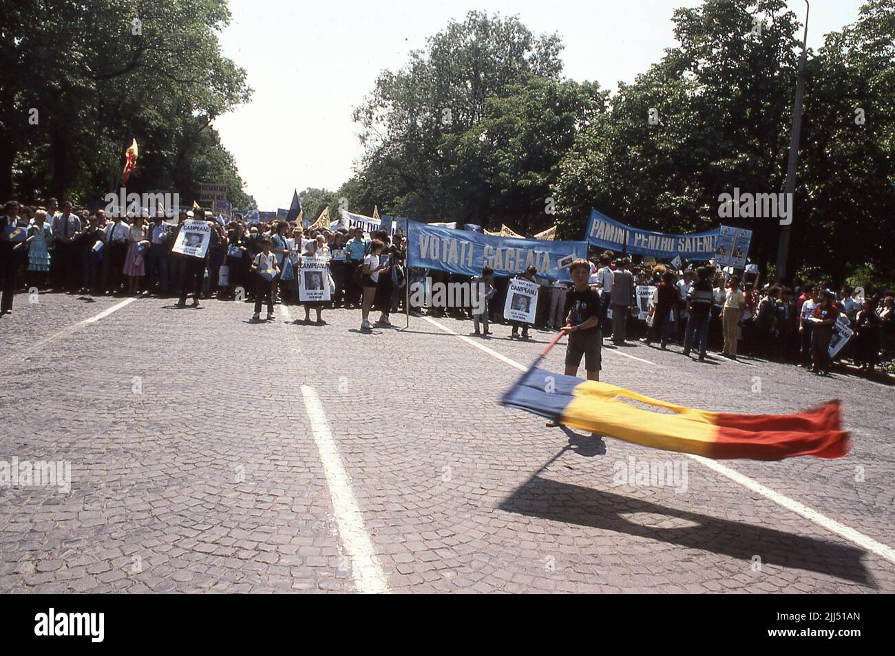 Bucharest, Romania, May 1990. Political rally organized by the National Liberal Party (PNL) days before the first democratic elections organized after the fall of communism. Person waving the Romanian flag with the Socialist emblem cut off, an anti-communist symbol during the Romanian Revolution of 1989. Stock Photo