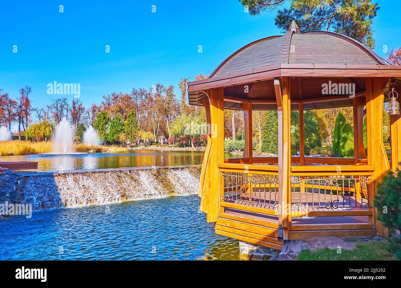 The beautiful wooden gazebo on the lake with small waterfall and