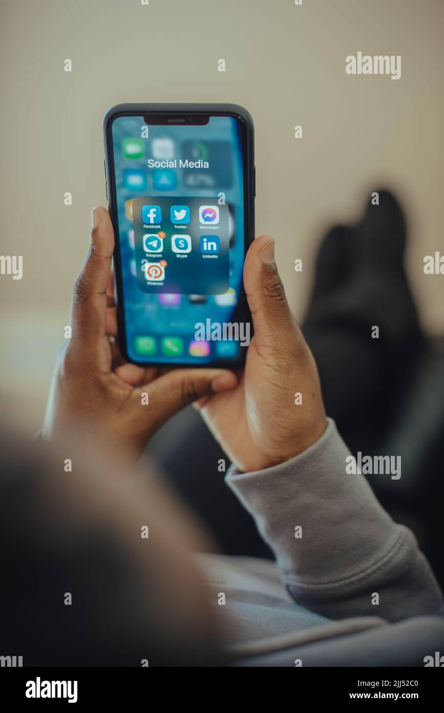 Hands of a person holding a mobile phone with social media icons