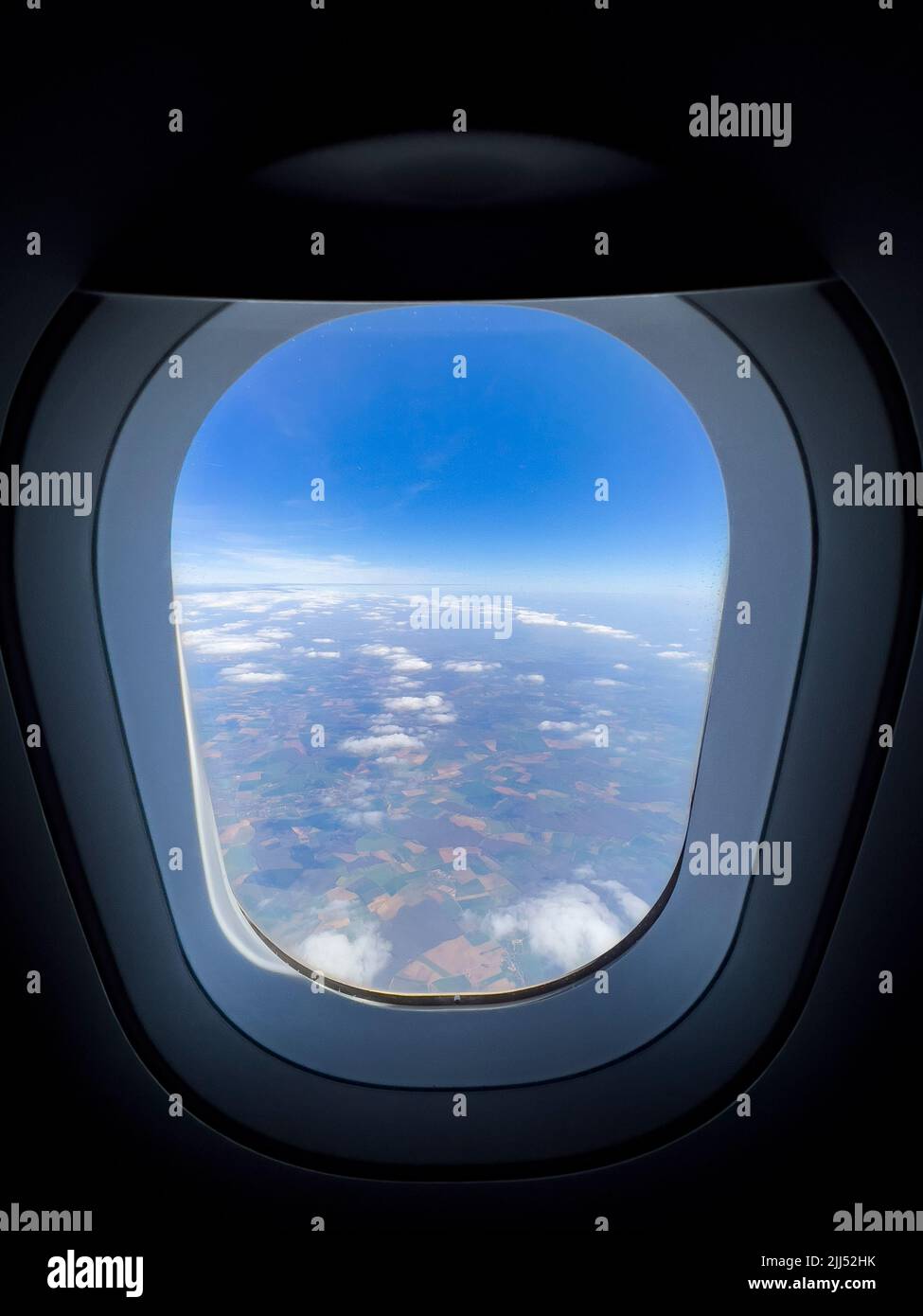 Beautiful scenery from the air through plane porthole. Bull's eye view on beautiful sky, black background, copy space. View from airplane window. Stock Photo