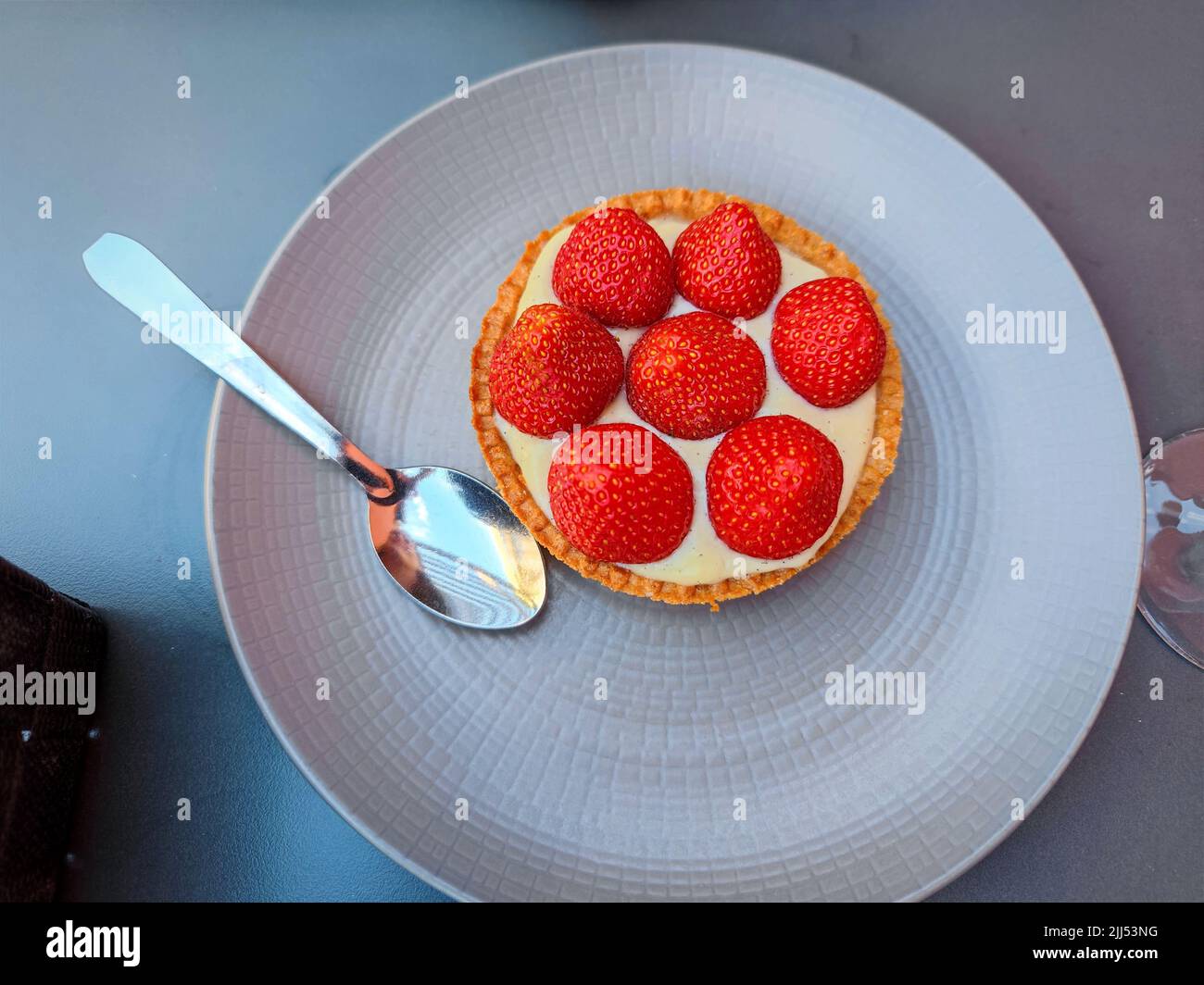 Small strawberry pie cake on a bowl on a restaurant table with a spoon next to it Stock Photo