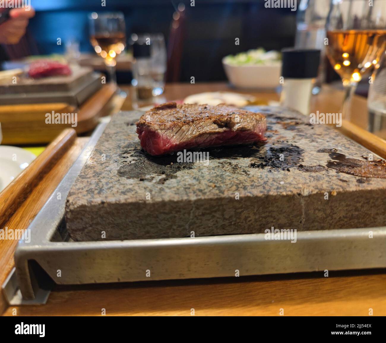 Steak is grilled on a stone grill with sauces in a restaurant on a dinner table Stock Photo