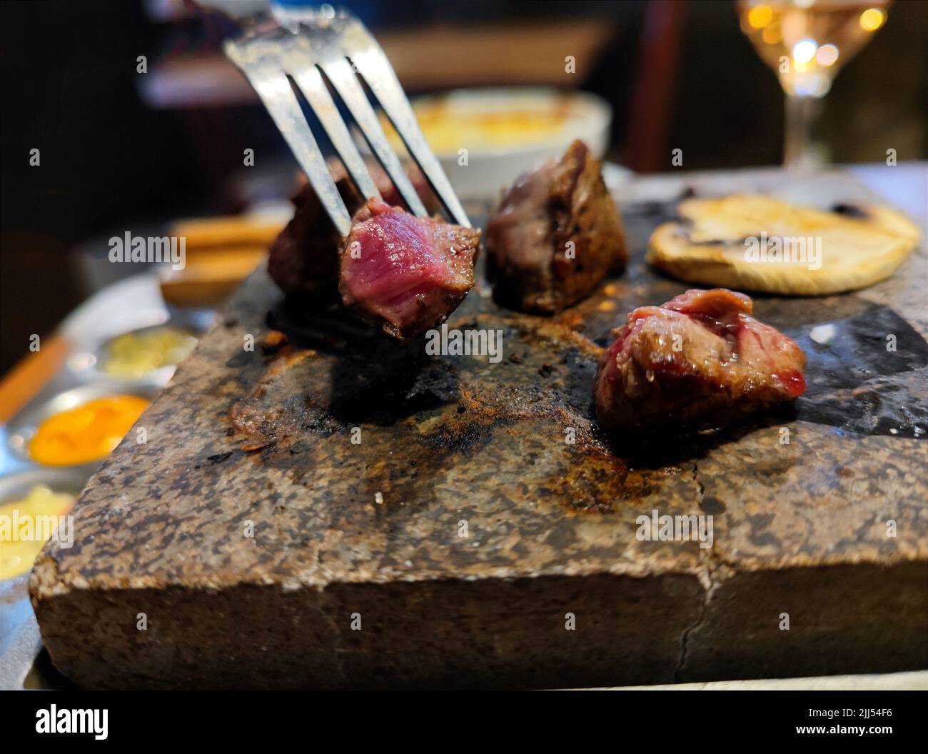 Close up of steak being grilled on a stone grill in a grill restaurant where people can grill their own meat on a hot stone Stock Photo