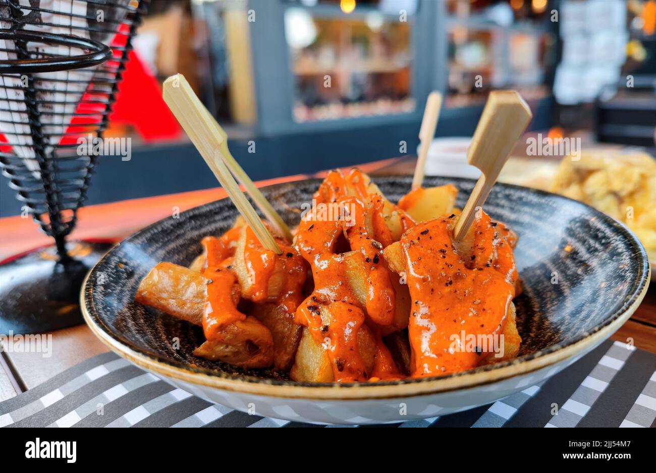 Delicious patatas bravas with spicy orange traditional sauce served on a black dish in a restaurant Stock Photo