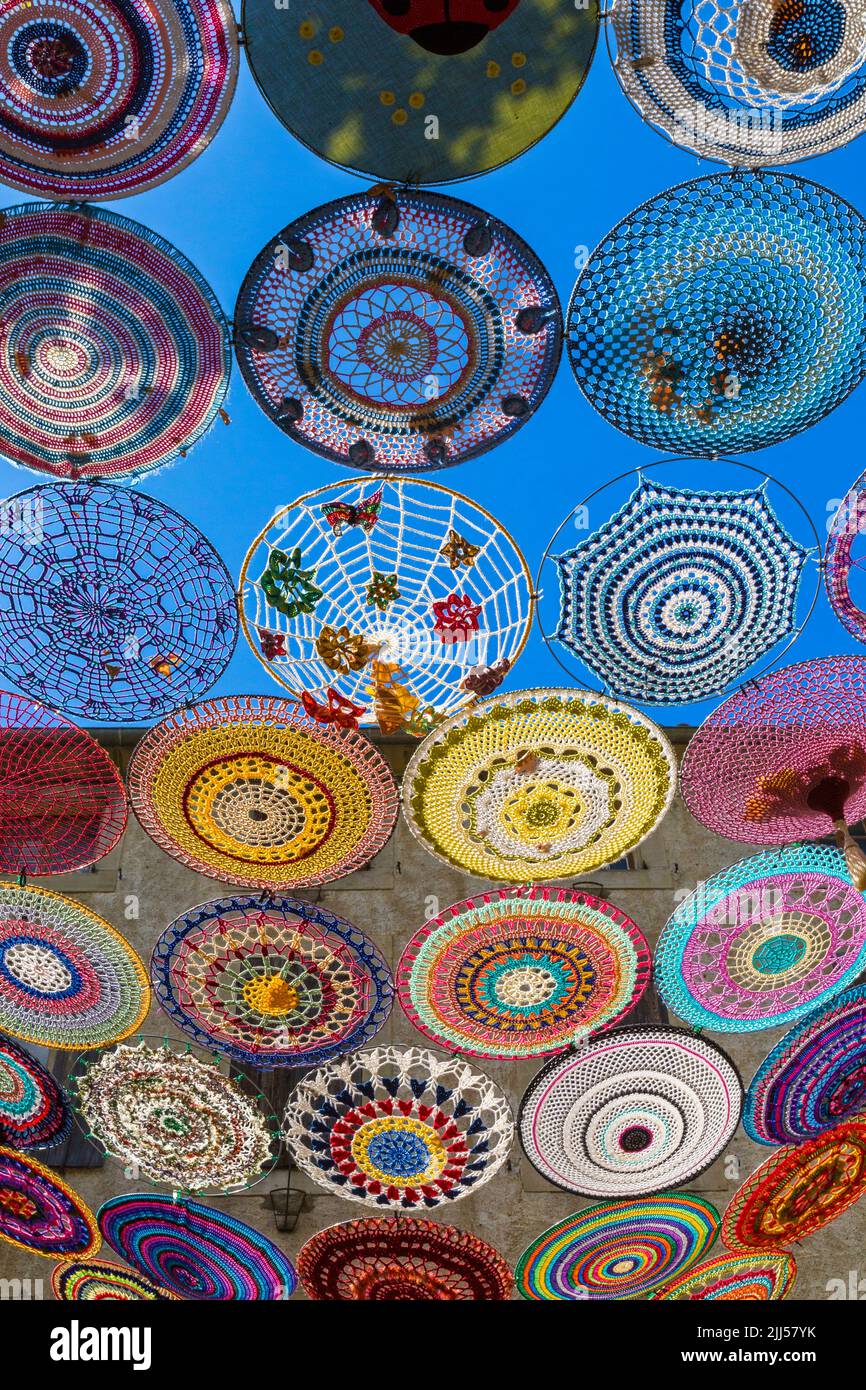 Decoration of the city with crocheted circles for the 'Chalabre en Serenade' music festival. On an idea of the American group 'The Riverbend Yarn Bombers', based in Illinois Mississippi. Work done by Julie Prochowski accompanied by a team of forty ladies from Chalabre and around the world. Chalabre, Occitanie, France Stock Photo